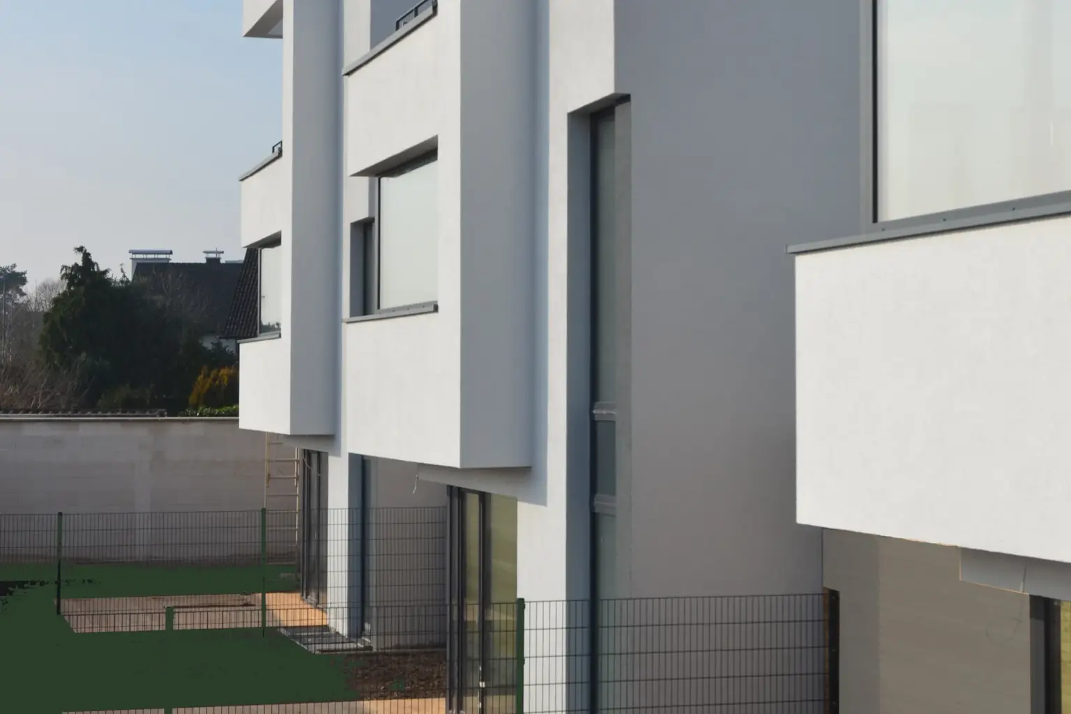 Detailansicht der gestaffelten Fassade moderner Wohnhäuser mit Fokus auf die klaren Linien und großen Fensterfronten.