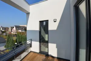 Blick auf eine moderne Dachterrasse mit Holzfußboden, dunklem Metallgeländer und Blick auf die umliegende Nachbarschaft.