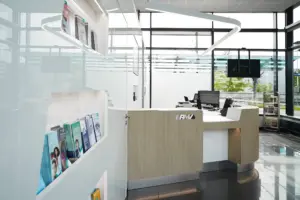 Detailansicht des Infobereichs mit integrierten Prospekthaltern in der weißen Wand und Blick durch die große Glasfront nach draußen.